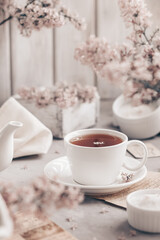 Cup of tea and lilac flowers on wooden table.
