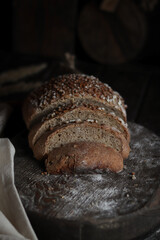 Loaf of bread, slice on the wooden background.