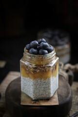 Chia pudding with nuts and blueberries in a jar on a wooden board