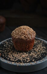 Chocolate muffin with caramel and chocolate chips on a dark background