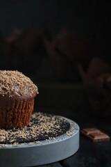 Chocolate muffin with caramel and chocolate chips on a dark background