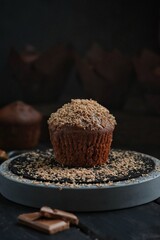 Chocolate muffin with caramel and chocolate chips on a dark background