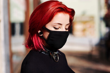 close up young adult woman outside with face mask blue eyes with punk spike choker redhead
