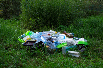 Garbage heap in the forest - plastic bottles and disposable containers. Addiction to plastic