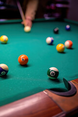 colored billiard balls with numbers on the billiard table in front of the pocket.