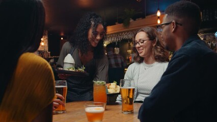 African American female waitress delivering food to customers table in restaurant