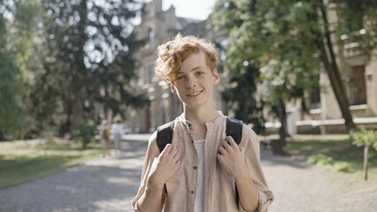 Cheerful red haired school boy smiling on camera, ready for classes, education