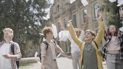 Excited school students throwing papers in air, celebrating successful test © Synthex
