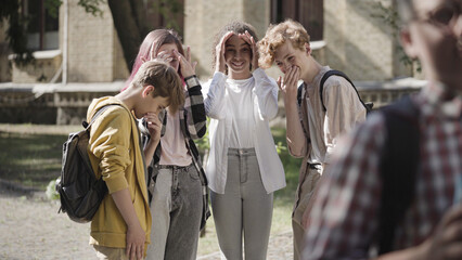 Fototapeta premium Group of school children gossiping and laughing at insecure classmate, bullying