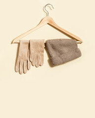 Beige knitted hat and suede gloves on clothes hanger Fashion warm clothing concept