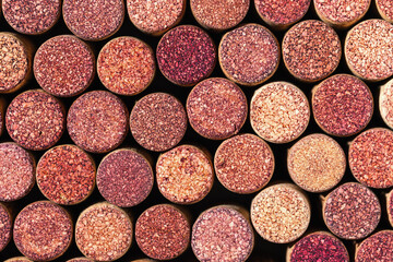 Wine cork background from red wine, natural texture used bottle stoppers top view. Closeup wooden red stain corks. Natural textured stoppers colored wallpaper. Bright background wine corks