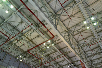 The steel construction roof of a sports hall and the spot lights on this roof. Wide shot of industrial hall empty and clean. Empty factory interior or storehouse