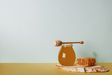 Honey background. Sweet honey in a glass jar and a honey spoon on a wooden table.  Copy space for...