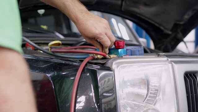 male car service worker fills up car air conditioner in service area and regulates supply of freon to system. Blue pressure gauges with red and blue knobs in process of service maintenance of vehicle.