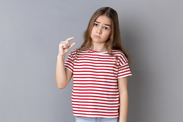 Need some more. Little girl wearing striped T-shirt doing a little bit gesture and looking with...