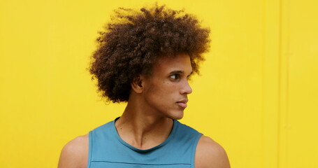 Obraz na płótnie Canvas Handsome mixed race young black man looking to camera with yellow background