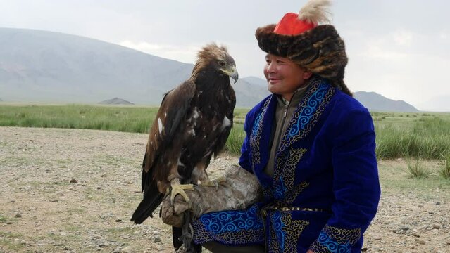 Kazakh Eagle Hunter in traditional clothing holding a golden eagle on his arm near Bayan-Olgii in West Mongolia.