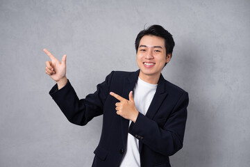 Young business man wearing a suit posing on a grey background