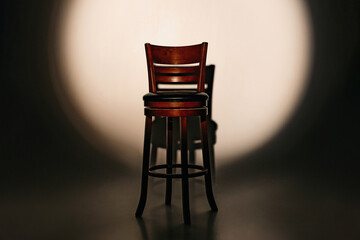 Empty chair on a dark background with a spot of light on the stage, recruiting, searching, vacancy,...