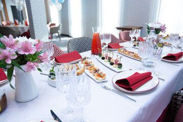 Beautiful table setting with dishes and flowers for a party, birthday, reception or other festive event. Glassware and cutlery for dinner.