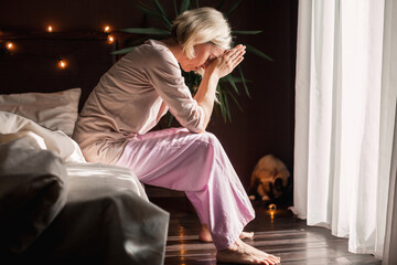Unhappy sad middle aged woman sitting on bed at home - obrazy, fototapety, plakaty