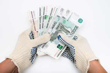 Hands of a worker, handyman, builder in protective gloves holding money, salary, payment for work in russian roubles