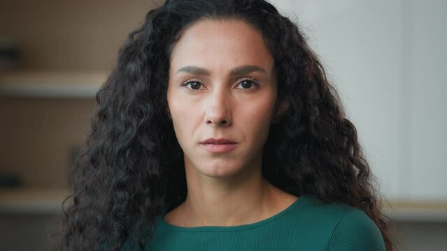Sad depressed woman arab hispanic upset wife stand alone in kitchen looking at camera with resentful offended facial expression worry about trouble problem victim of domestic violence bullying racism