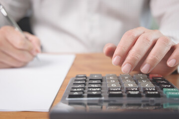 Closeup of businessman hand woking with calculator to calculate the business investment profit, tax and financial status. Business accounting analysis and income report concept.