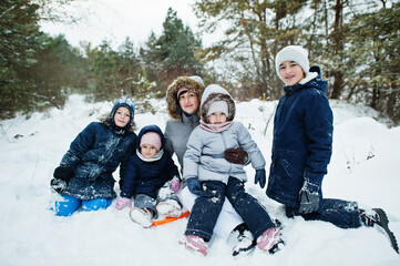 Mother with four children in winter nature. Outdoors in snow.