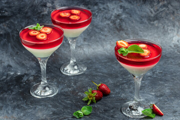 Traditional Italian dessert panna cotta with strawberry jelly on a dark background. Summer yogurt dessert. Long banner format. space for text