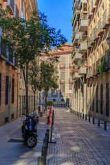 Beautiful traditional residential buildings with metal balconies on a narrow cobblestone street of the city center in Madrid, Spain