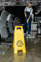 selective focus of attention sign board near cleaner washing floor on blurred background.