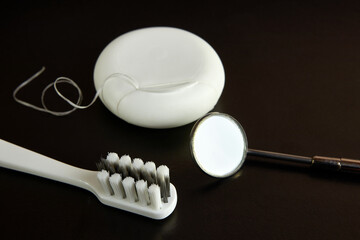 Dental mirror, dental floss and toothbrush on a black background. Dental care.