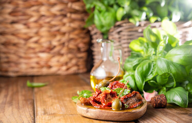 Dried tomatoes with herbs and olive oil. Traditional canned tomatoes in Italy with garlic, Provence herbs and basil. Ingredients for bruschetta and aperitif. Top view, space for text