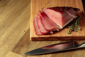 Dry-cured pork with thyme on a wooden cutting board.