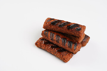 Traditional south european skinless sausages cevapcici made of ground meat and spices, vegan substitute made of soy protein, stacked on white background