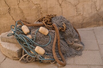 Heap of fish mesh traps on wall background. Braided fishing net from fibers woven in a grid-like structure with floats.