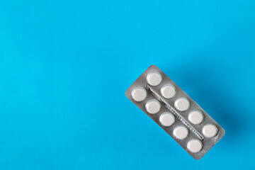 white tablets in a package, with a shadow, on a blue background, space for text