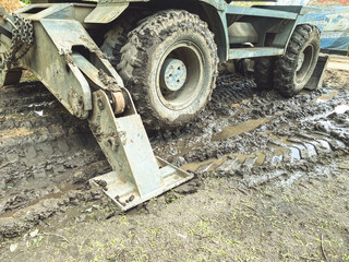 Fototapeta na wymiar a tractor with large, black wheels in the mud. metal anchor to hold the machine in place. black wheel stuck in a puddle of mud