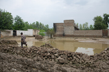 the ruins of the city after flash flood in Pakistan, children tread around the heavy mud