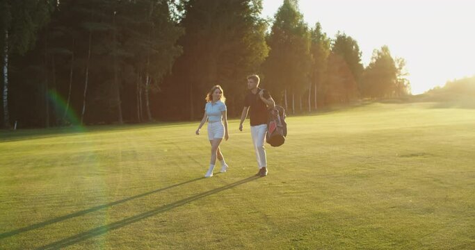 Golfer and caddy walking towards the field. They talk about different topics. High quality 4k footage