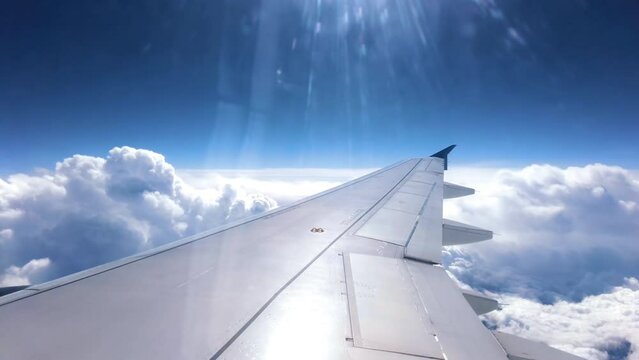 Aircraft wing and blue sky with white clouds during a flight