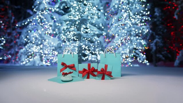 Magical snowy Merry Christmas night. Happy New Year 2023 blue elegant gift boxes with red bows on fancy decorated Christmas trees blurred background. Scenic Christmas eve celebration concept, RED shot