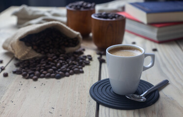Taza de café, libros de texto y dos cuencos con granos de café