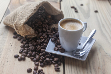 Taza de café sobre un platillo blanco y granos de café tostado