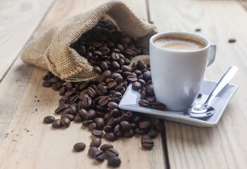 Taza de café junto a un saco con granos de cafe
