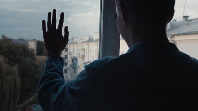 boy's hand moves down the window against the backdrop of soviet houses, no war, war in Ukraine