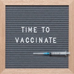 Time to vaccinate text on letter board with disposable syringe. Health concept.