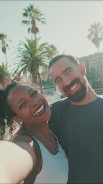 VERTICAL VIDEO: Close-up of interracial smiling couple in love taking selfie