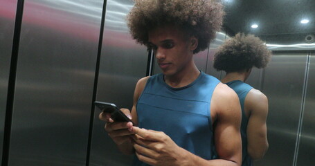 Young african black man checking cellphone device inside elevator, person stepping out of elevator transportation
